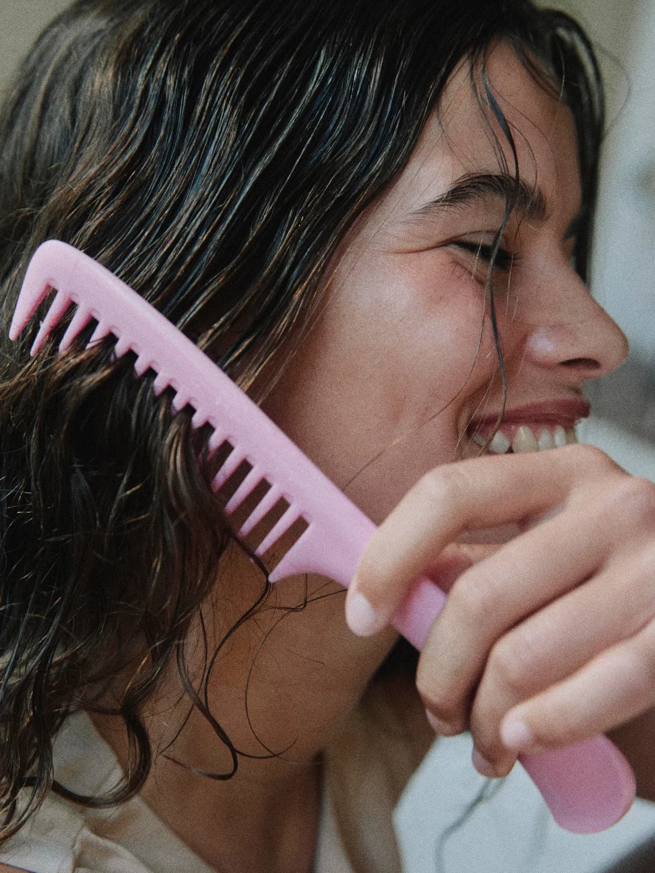 Mujer peinando su cabello húmedo después de un tratamiento capilar